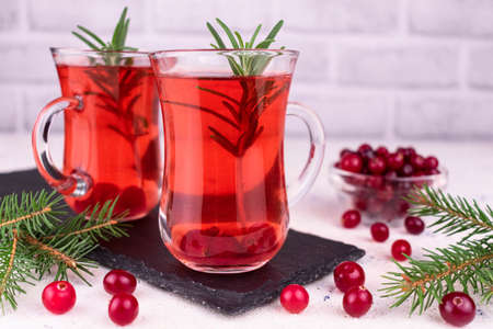 Cranberry cocktail with a sprig of rosemary on a white background.