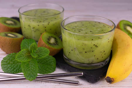 Kiwi banana smoothie on a white wooden background.の写真素材