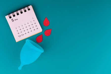 Menstrual cup and calendar on a blue background.の写真素材