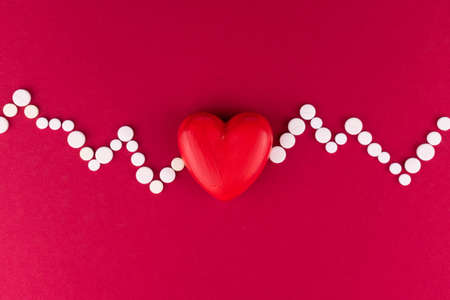 Cardiogram heart made from pills on a red background. The concept of heart disease.