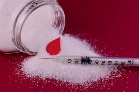 Sugar and insulin syringe on a red background. Diabetes concept.