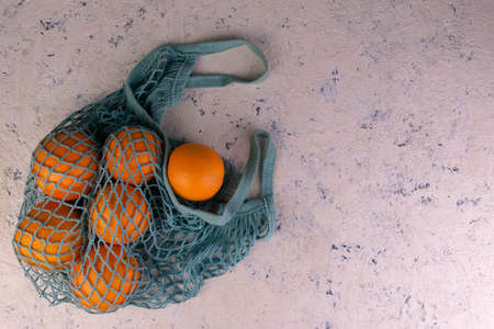 Oranges in a blue eco-bag. Modern reusable shopping, zero waste concept.Copy space.