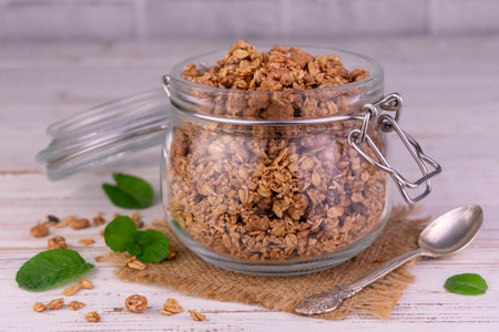 Homemade granola in a glass jar on a white wooden backgroundの写真素材