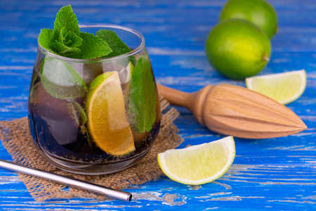 Cocktail Cuba Libre with lime, rum, mint and ice on an old blue wooden background.の写真素材