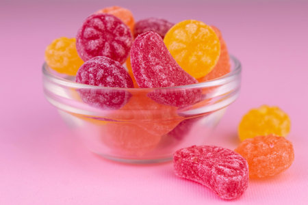 Multi-colored candies in a glass vase on a pink background. close-up.