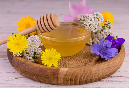 Fresh floral honey with a glass bowl on a wooden tray.の写真素材