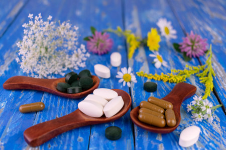 Homeopathic medicines and medicinal herbs on a blue wooden table.の写真素材