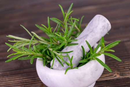 Rosemary in a stone mortar on a wooden background.の写真素材