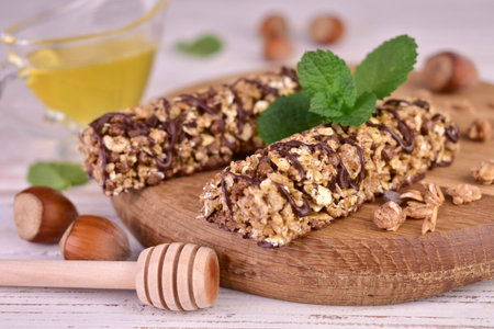 Two muesli bars with chocolate and honey on a wooden board.の写真素材