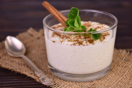 Rice pudding with cinnamon in a glass on a dark wooden background.Close-up.の素材