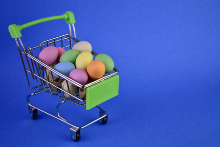 Easter eggs in a shopping basket on a blue background.Copy space.の素材