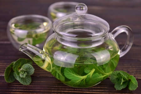 Teapot with mint tea on a dark wooden background.の写真素材