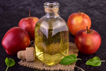 Apple cider vinegar and fresh apple on a black background.の写真素材