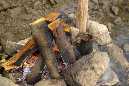 Aromatic and hot coffee on the fire. Bonfire and thermo mugs. Bonfire on the river bank.の写真素材