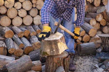 Man holding an industrial ax. Ax in hand. A chain of chains and firewood. Strong man lumberjack with an ax in his hand. Chainsaw close up.の写真素材