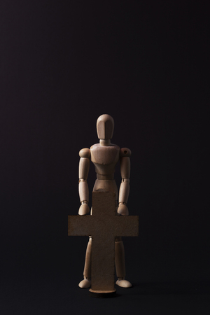 Wooden man. A wooden man holds a cross. Cross. Cross in hand.の写真素材