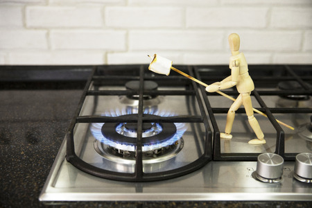 Cook marshmallows on fire. Wooden mannequin. Wooden mannequin preparing marshmallows on fire.の写真素材