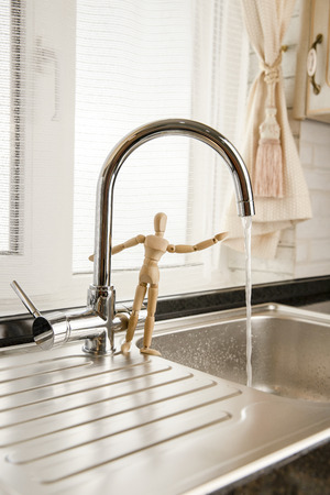 Mixer close up. Faucet with flowing water. Concept Save Energy Water. Water Drop from Tap. Mixer. Wooden mannequin. Wooden man.の写真素材