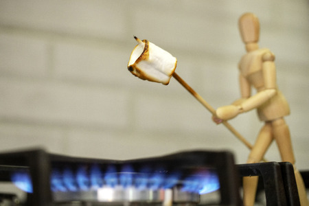 Wooden mannequin preparing marshmallows on fire. Cook marshmallows on fire. Wooden mannequin. Wooden mannequin. Wooden man.の写真素材