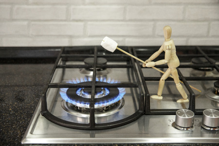 Wooden mannequin preparing marshmallows on fire. Cook marshmallows on fire. Wooden mannequin. Wooden mannequin. Wooden man.の写真素材