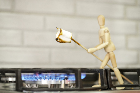 Wooden mannequin preparing marshmallows on fire. Cook marshmallows on fire. Wooden mannequin. Wooden mannequin. Wooden man.の写真素材