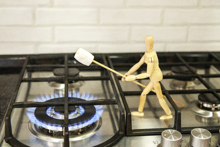 Wooden mannequin preparing marshmallows on fire. Cook marshmallows on fire. Wooden mannequin. Wooden mannequin. Wooden man.の写真素材