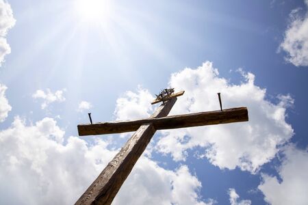 The Cross with bright sun and clouds in the background. Wood cross on blue sky. Christian background.の写真素材