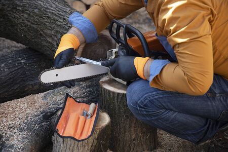 Sharpening a chainsaw Close up on a man sharpening a chainsaw chain with file.の写真素材