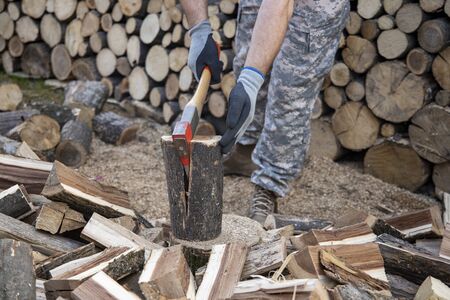 Man holding an industrial ax. Ax in hand. A strong man holds an ax in his hands against the background of chainsaws and firewood. Strong man lumberjack with an ax in his hand.の写真素材