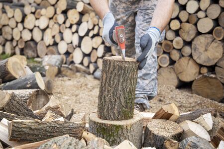 Man holding an industrial ax. Ax in hand. A strong man holds an ax in his hands against the background of chainsaws and firewood. Strong man lumberjack with an ax in his hand.の写真素材