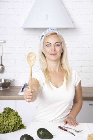 Girl holds a spoon in the shape of a heart. Cook With love. A young girl is cooking in the kitchen.の写真素材