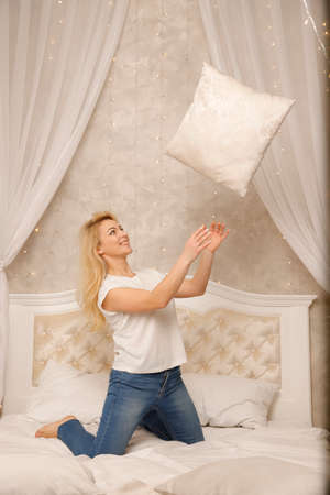 Happy playful young man and woman playing pillow fight at home, laughing loving couple having fun in bedroom, smiling wife and husband spending leisure free time together, enjoying weekendの写真素材