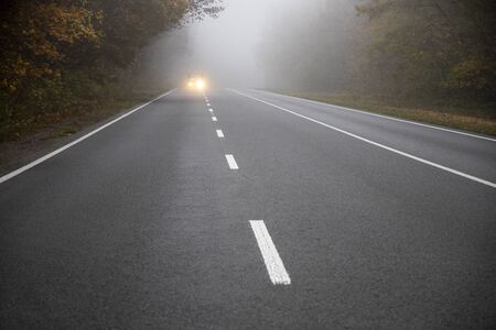 Car on the road in the fog. Autumn landscape.の写真素材