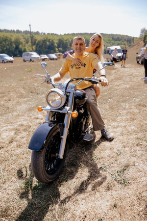 Young couple sitting on a chopper motorbike in the field.の写真素材