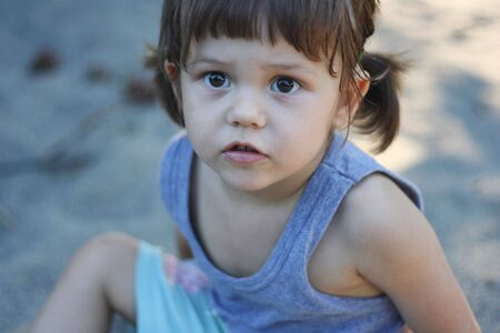 little girl sitting in the sandの写真素材