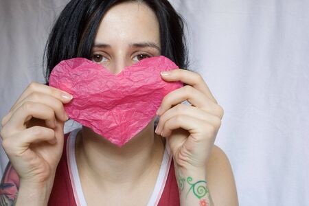 portrait of a girl with pink heart in her handsの写真素材