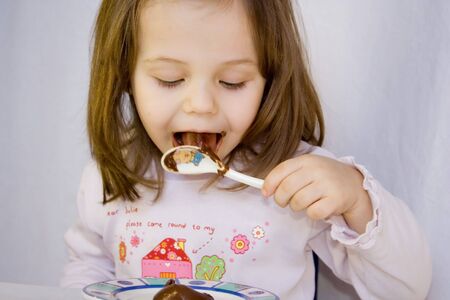 little girl eating the chocolateの写真素材