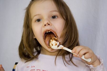 little girl eating the chocolateの写真素材