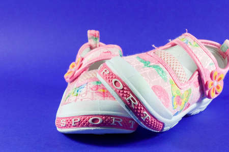 cute, pink sneakers with floral pattern isolated on blueの写真素材