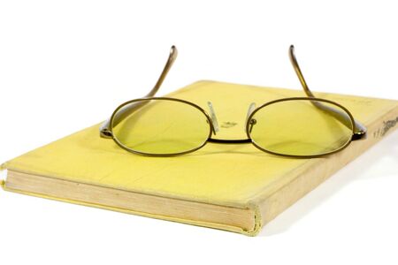 Yellow book and eyeglasses isolated on whiteの写真素材