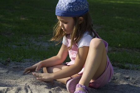 little girl playing on the playground in the rays of sunの写真素材
