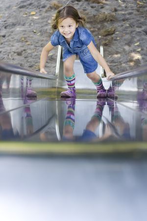 little girl wearing a blue dress climbing on the slideの写真素材