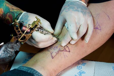 man wearing gloves and making a tattoo