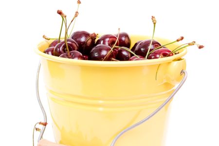 red cherries in a bucket isolated on whiteの写真素材