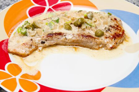 fried steak with caper sauce on the plateの写真素材