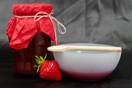 Glass pot with strawberry jam against black backgroundの写真素材