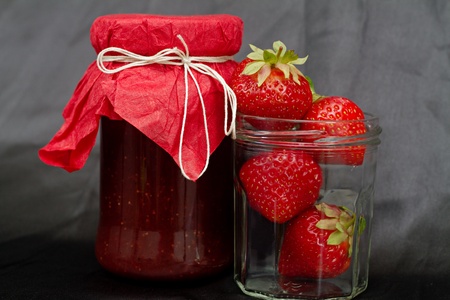 Glass pot with strawberry jam against black backgroundの写真素材