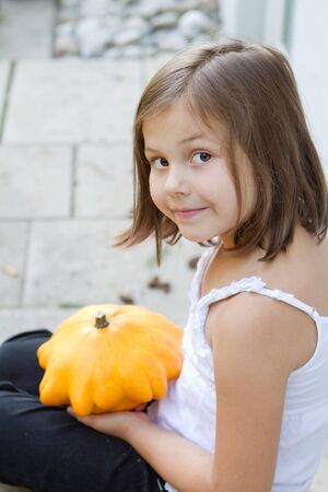 little, caucasian girl holding pumpkin in her handsの写真素材