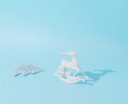 White reindeer and Christmas tree on a pastel blue background. Conceptual setting.の写真素材