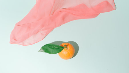 The pink scarf falls towards the orange with green leaves. The background is blue like a clear sky.の写真素材